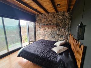 Un dormitorio con una cama con una pared de piedra. en Chalet - Stone Cabin, en Villa Icho Cruz