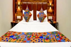a bedroom with a bed with a colorful quilt on it at Hotel Golden Sands Inn Aslpha in Mumbai