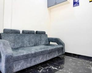 a gray couch sitting in a room next to a wall at Hotel Golden Sands Inn Aslpha in Mumbai