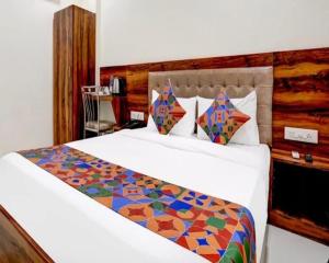 a bedroom with a white bed with a colorful comforter at Hotel Golden Sands Inn Aslpha in Mumbai