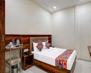a bedroom with a bed and a table and a phone at Hotel Golden Sands Inn Aslpha in Mumbai