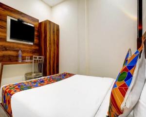 a bedroom with a bed and a tv on a wall at Hotel Golden Sands Inn Aslpha in Mumbai