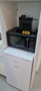 a black microwave sitting on top of a white refrigerator at Desert Shine in Qiryat Gat