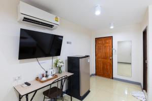 a room with a refrigerator and a table with a television at PMS Boutique Patong in Patong Beach