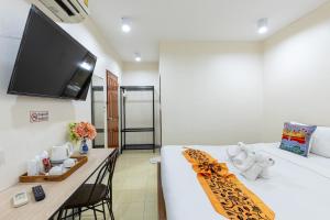 a room with a bed with a desk and a flat screen tv at PMS Boutique Patong in Patong Beach