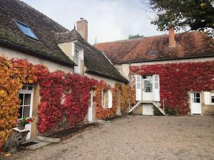a building covered in red ivy next to a house at Grande maison avec piscine in Limoise