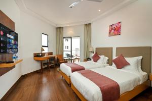 a hotel room with two beds and a desk at Hotel Maharaja Regency in Satara