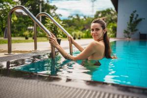 Una donna in una piscina che scende da una scala di metallo di Lion Gate Hotel Sigiriya a Sigiriya