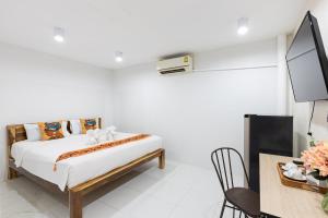 a bedroom with a bed and a table and a tv at PMS Boutique Patong in Patong Beach