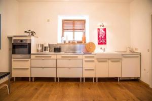 a large kitchen with white cabinets and a window at Ferienwohnung Altes Schulhaus Greising in Deggendorf +17 photos