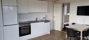 a kitchen with white cabinets and a table with chairs at Premium hytte med udendørs spa in Farsø