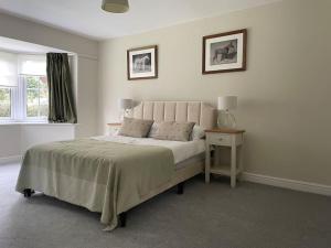 a white bedroom with a bed and a nightstand and a window at Spacious, Modern Bungalow in Newton Regis