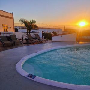 a large swimming pool with a sunset in the background at Casa Tazirit in Mácher