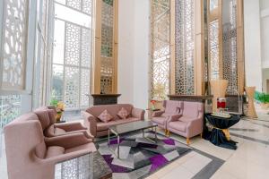 eine Lobby mit rosa Stühlen, Tischen und Fenstern in der Unterkunft Adya Hotel Langkawi in Kuah