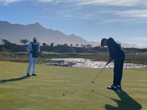 two people playing golf on a golf course at House Susan Pardew Hersham in Great Brak River