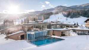 a house in the snow with a swimming pool at Naturresort PURADIES in Leogang