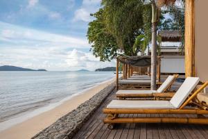 a row of lounge chairs on a beach at Serenity Rawai by Destada in Rawai Beach