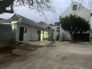 a white house with a tree in front of it at Heba Guest Lodge Two in Uitenhage