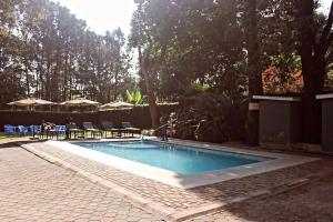 a swimming pool in a yard with chairs and umbrellas at Destination 3Degrees Hotel in Arusha