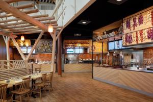 a restaurant with tables and chairs and a kitchen at Center Parcs Les Landes de Gascogne in Beauziac