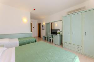 a hotel room with two beds and a desk at Paglianza Hotel in Peschici