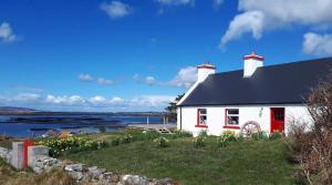 Casa blanca con techo negro y puertas rojas en The Sea House, en Dungloe