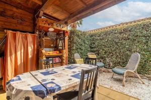 a patio with a table and chairs and a hedge at Appartement Avec Jardin et piscine in Narbonne