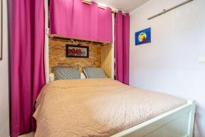 a bed in a room with pink curtains at Appartement Avec Jardin et piscine in Narbonne