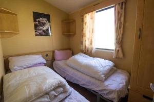 a small room with two beds and a window at Lovely 6 Berth Caravan At Naze Marine Holiday Park In Essex Ref 17275C in Walton-on-the-Naze