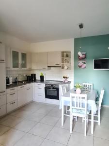 a kitchen with white cabinets and a table and chairs at Ferienwohnung am Hünenweg in Berge
