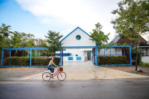 a woman riding a bike in front of a house at Standard in Ban Phrom Min
