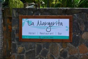 a sign for a hotel restaurant bar on a stone wall at La Margarita in Pointe aux Piments