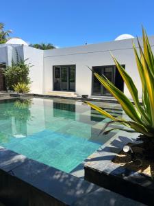 a swimming pool in front of a house at Blue Palm Villa with Private Pool & Tropical Garden in Cap Malheureux
