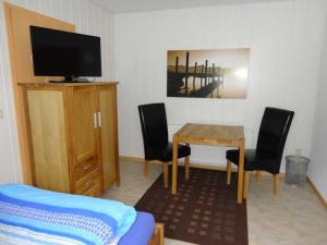 ein Wohnzimmer mit Tisch, Stühlen und Fernseher in der Unterkunft 2 Einbettzimmer in Neubrandenburg