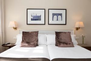 a bedroom with a white bed with two pictures on the wall at Hotel San Antonio el Real in Segovia +83 photos
