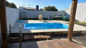 a swimming pool in a backyard with a table and chairs at Casa piscina MAJU in Imbé