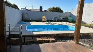 a swimming pool in a backyard with a table and chairs at Casa piscina MAJU in Imbé