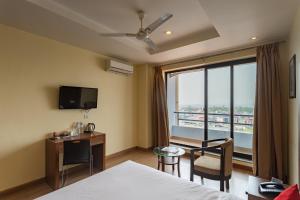 Una habitación de hotel con una cama, un escritorio y una ventana. en Hotel Verandah, en Itahari