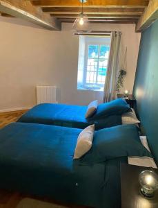 een slaapkamer met twee blauwe bedden en een raam bij Le Colombier d Yville in Héronchelles +24 foto's