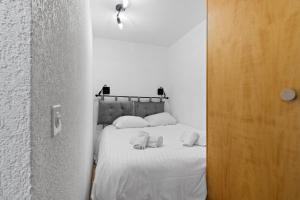 a bedroom with a bed with white sheets and pillows at Charmant studio à côté des pistes de ski in Nendaz