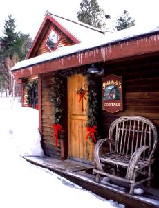 a wooden cabin with a bench in the snow at Goldilocks Cabin in Stowe
