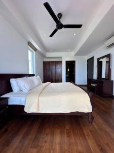 ein Schlafzimmer mit einem Bett mit Deckenventilator in der Unterkunft Nilaveli Condos by Amba in Nilaveli