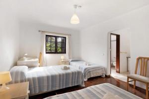 a white room with two beds and a mirror at Alto da Praia Villa in Colares