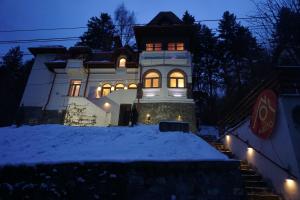 a house with lights on in the snow at night at Vila Arizto in Sinaia