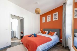 a bedroom with a bed with an orange wall at Maisonnette au cœur de Cognac in Cognac