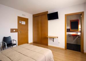 a bedroom with a bed and a chair and a television at Reigosa II in Pontevedra