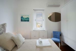 a white bedroom with a bed and a blue chair at Casa Dalù in Positano
