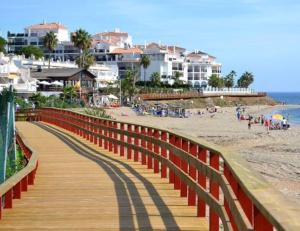 a wooden boardwalk leading to a beach with condos at Perfekt lokation! Gå til strand, restaurant og by in Sitio de Calahonda