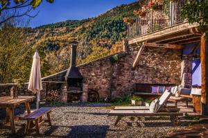 an outdoor patio with a stone building with an outdoor fireplace at Cal Sodhi in Argestues