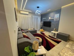 a living room with a couch and a tv at Celia -1 Bedroom Beauty in Madīnat al Amal